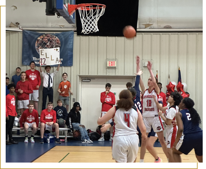 A group of people playing basketball in front of an audience.