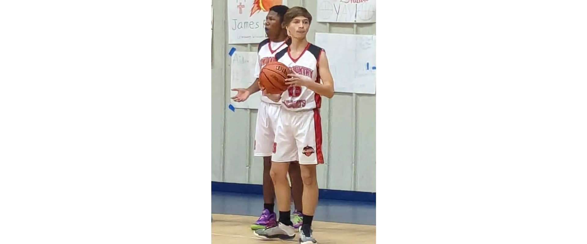 Two young men are playing basketball on a court.