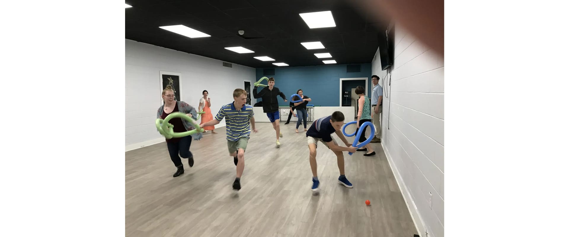 A group of people playing with frisbees in an exercise room.