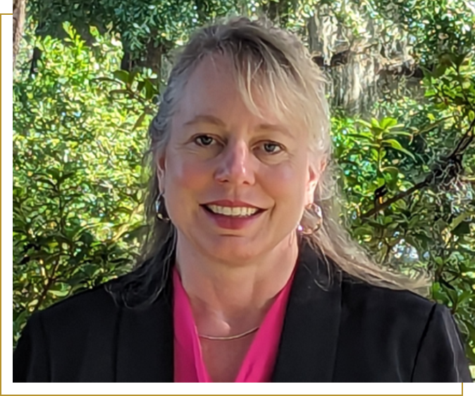 A woman with long blonde hair wearing a black jacket.