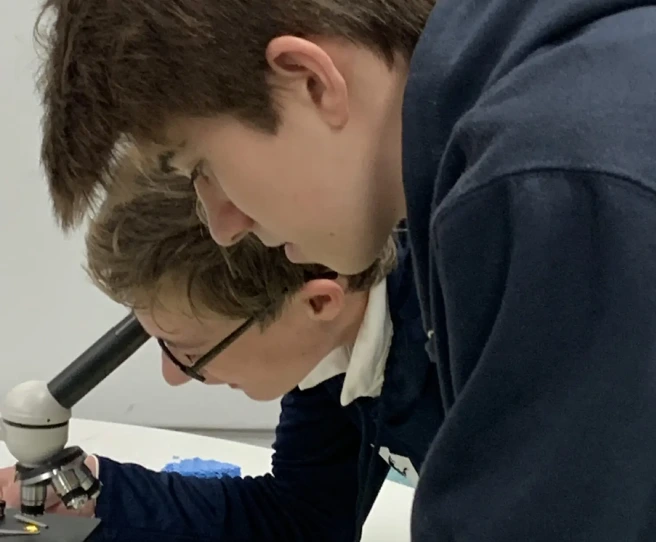 Two young men looking at a microscope in a lab.