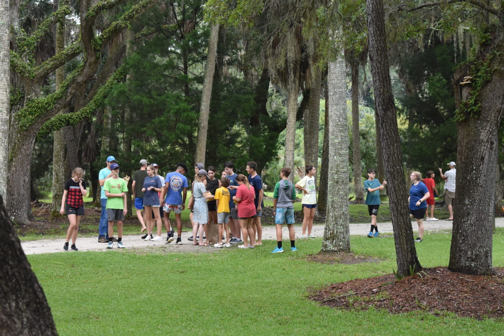 A group of people standing around in the grass.