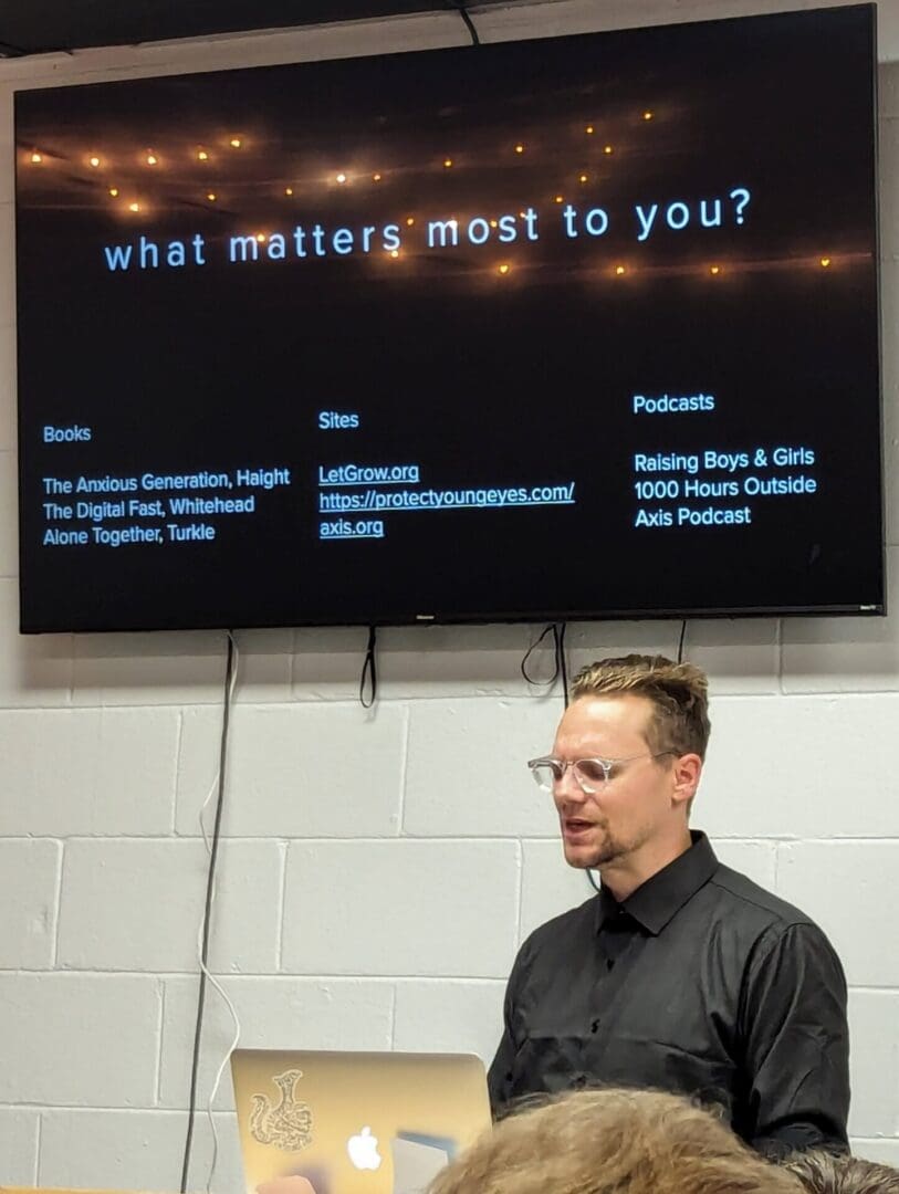 A man standing in front of a large screen.