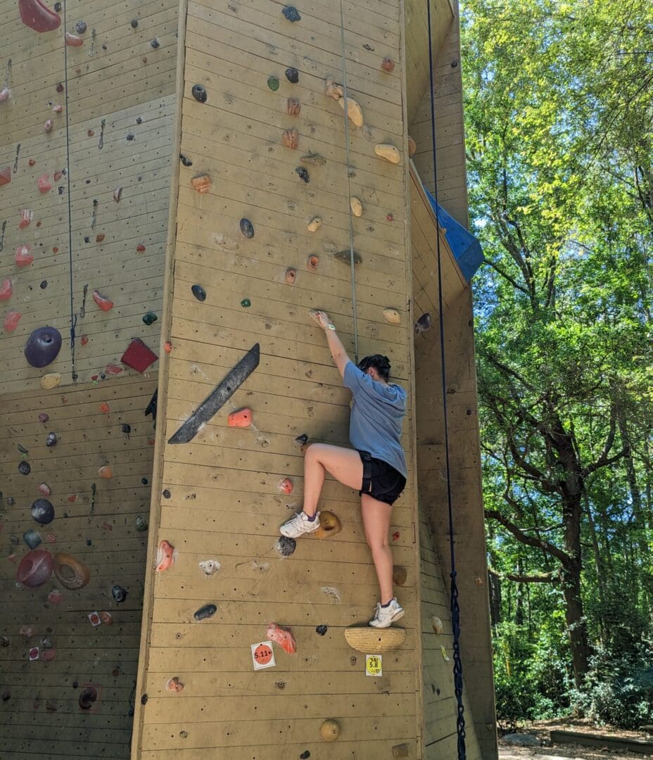 A woman climbing up the side of a rock wall.