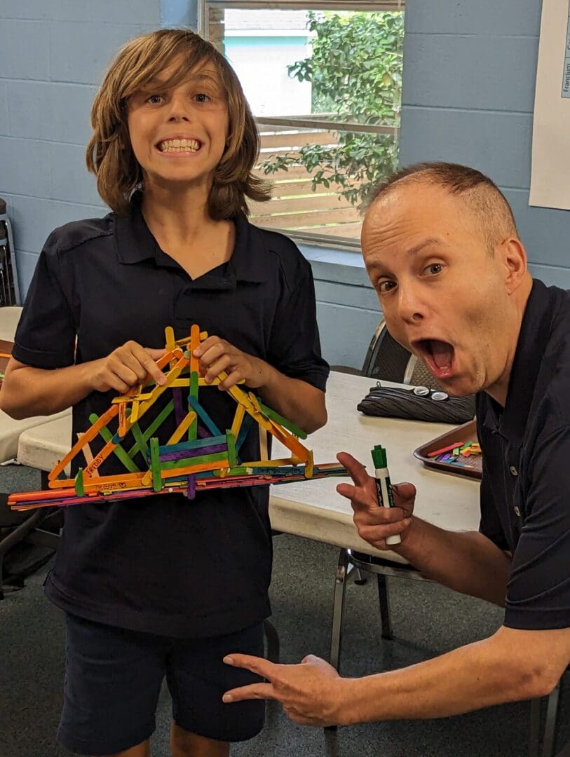 A man and woman holding up a toy bridge.