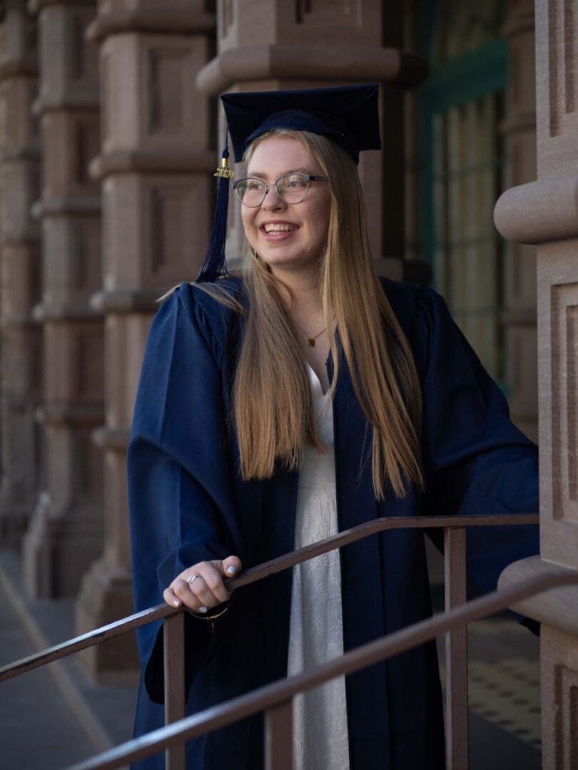 A woman in graduation gown and cap smiling.