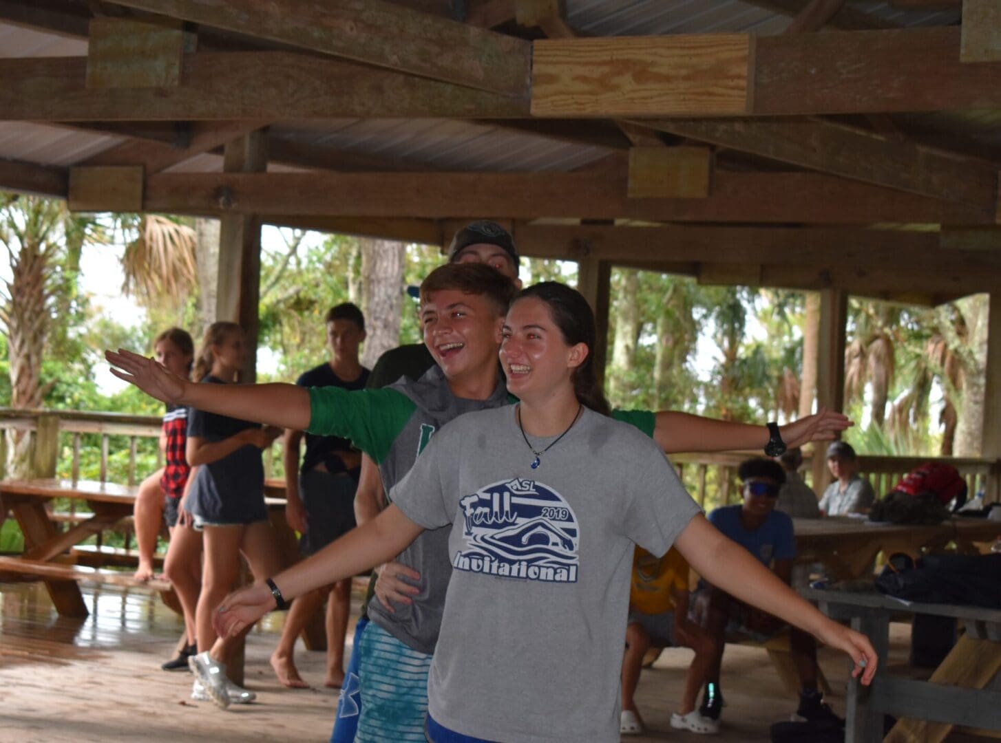 A group of people standing under a wooden structure.