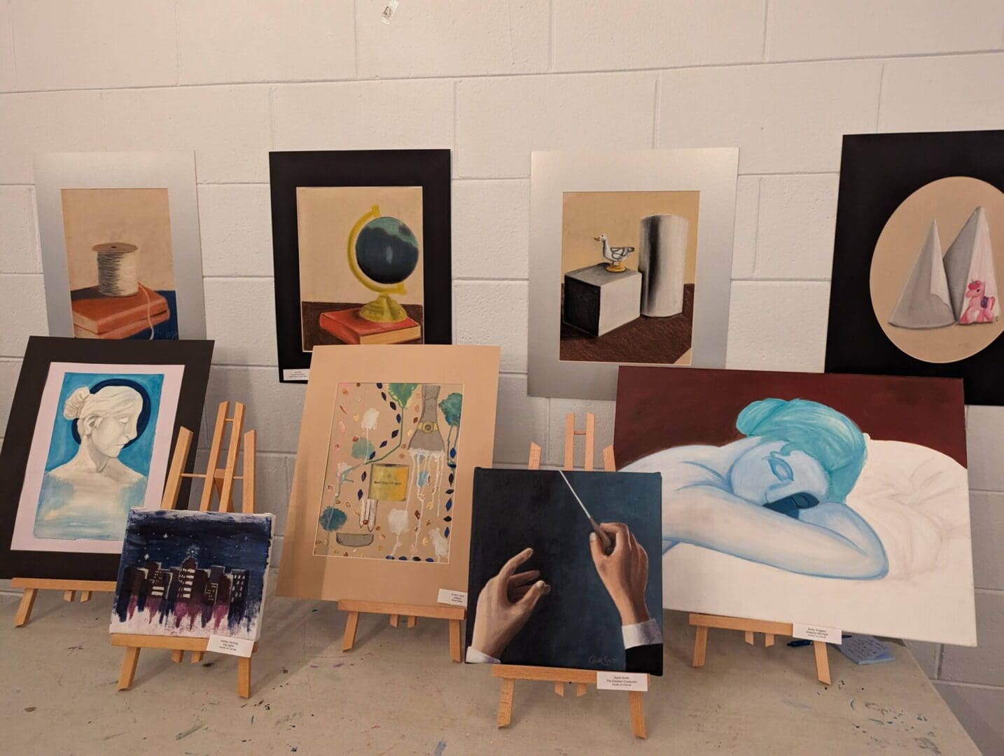 A group of paintings on display in front of a wall.