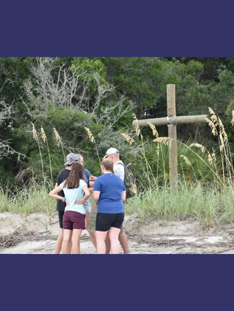 Three women standing in front of a cross.