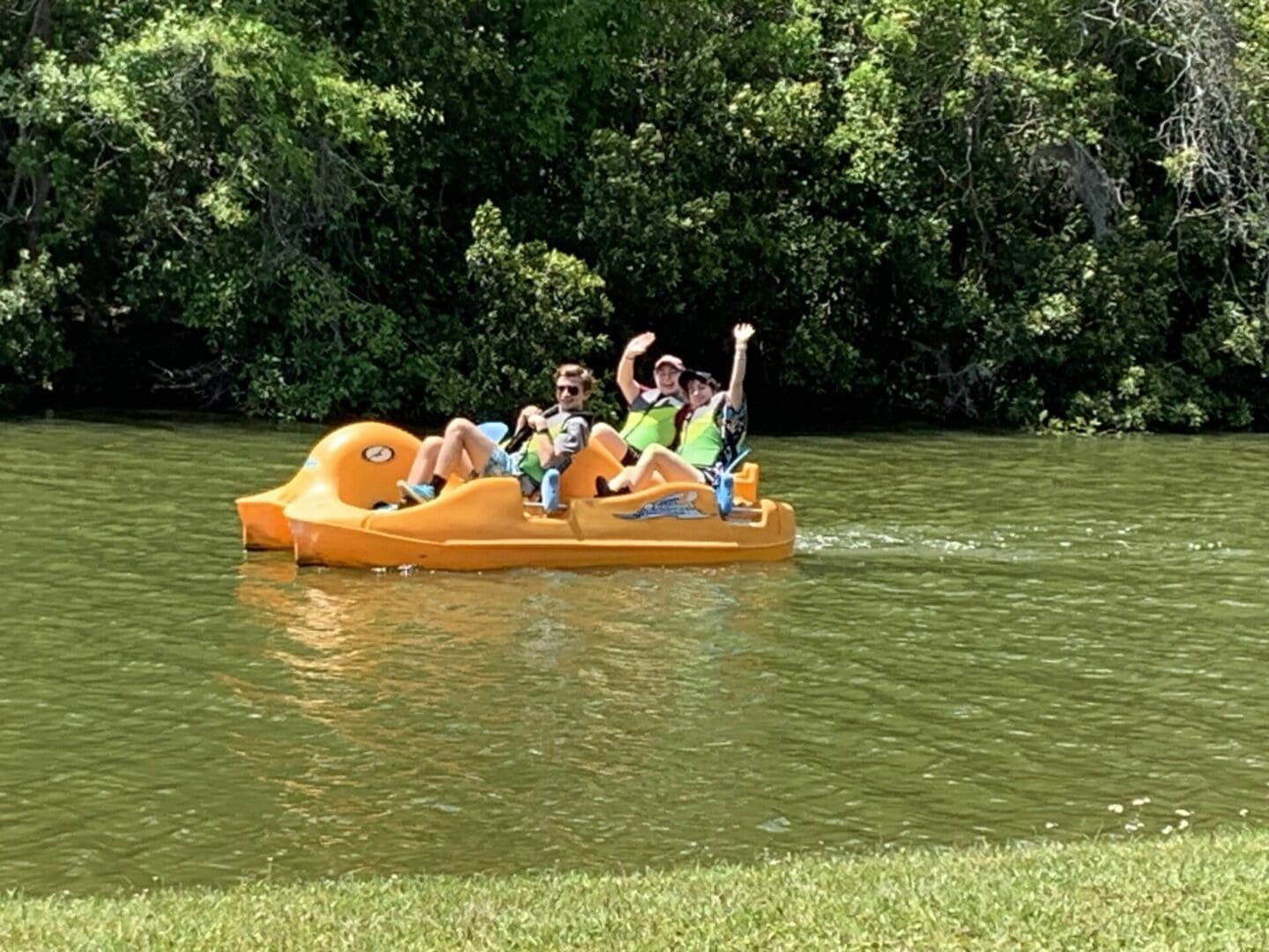 A group of people riding on the back of an orange raft.