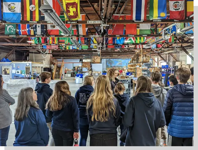 A group of people standing under flags in an indoor area.