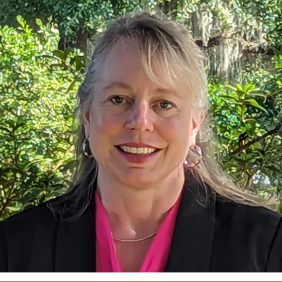 A woman with long blonde hair wearing a black jacket.